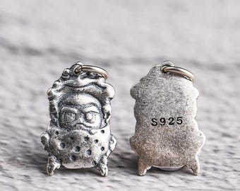 May include: Two silver pendants, each in the shape of a stylized figure. One pendant shows the front of the figure with facial features and a textured design. The other pendant shows the back with the text "S925". Both pendants have a small loop at the top.