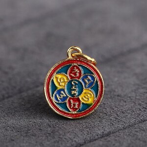 Puede incluir: Pendiente de oro con un dise&ntilde;o redondo de esmalte azul, rojo y amarillo. El pendiente presenta cinco s&iacute;mbolos en forma de flor.