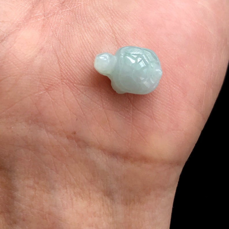 May include: A small, light green jade turtle figurine. The turtle is carved in detail and has a smooth, polished finish.