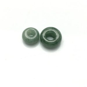 May include: Two green jade donut beads with a hole in the center. The beads are different sizes.