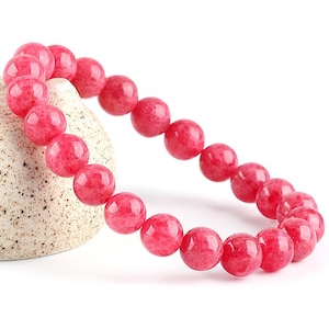 May include: A pink gemstone bracelet with round beads. The bracelet is made of natural stones and is a beautiful accessory for any occasion.