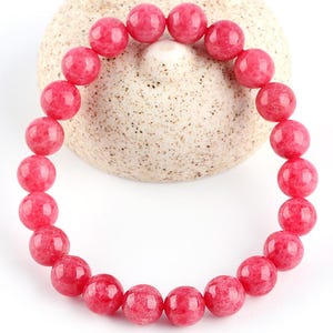 May include: A pink gemstone bracelet with round beads. The bracelet is made of natural stones and is a beautiful accessory for any occasion.