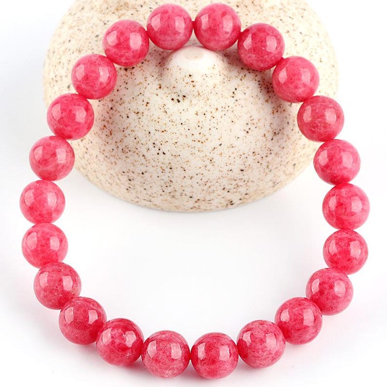 May include: A pink gemstone bracelet with round beads. The bracelet is made of natural stones and is a beautiful accessory for any occasion.
