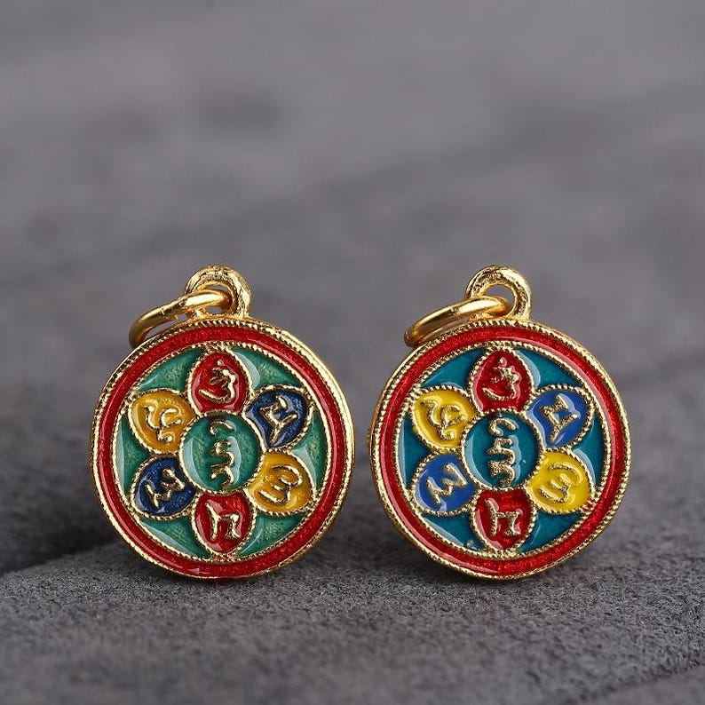 Puede incluir: Dos colgantes de oro con un dise&ntilde;o de esmalte rojo, azul, verde y amarillo. Cada colgante presenta un dise&ntilde;o circular con cinco p&eacute;talos y un s&iacute;mbolo en cada p&eacute;talo. Los s&iacute;mbolos son de color dorado.