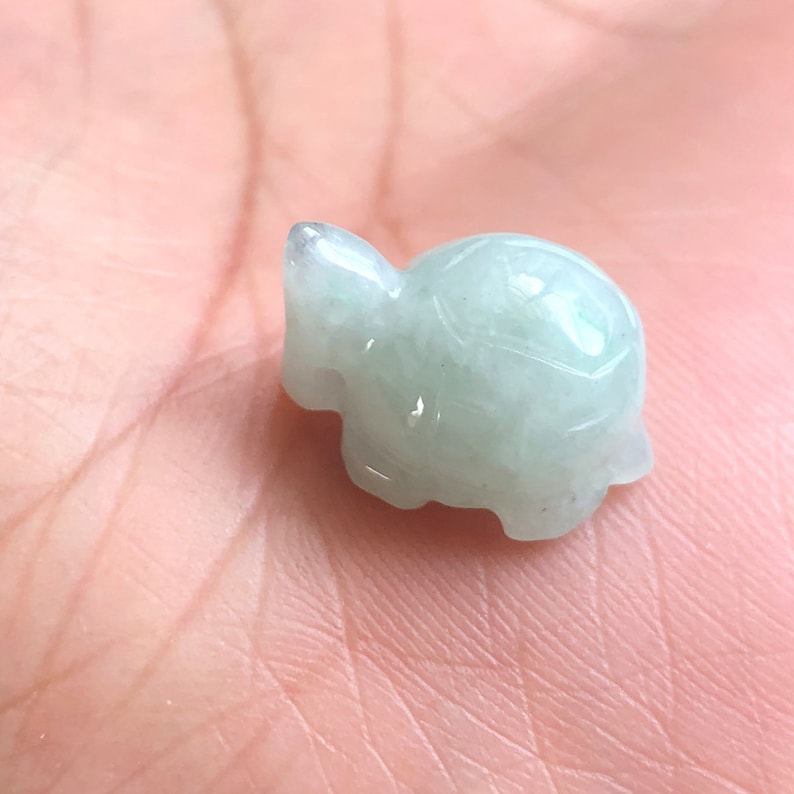 May include: A small, light green jade turtle figurine. The turtle is carved in a realistic style and has a smooth, polished finish.