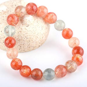 Op de afbeelding: Een armband gemaakt van ronde, oranje en heldere sunstone kralen. De kralen zijn ongeveer 1 cm in diameter en hebben een natuurlijke, gepolijste afwerking.