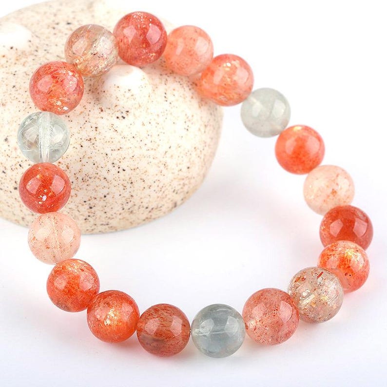 Op de afbeelding: Een armband gemaakt van ronde, oranje en heldere sunstone kralen. De kralen zijn ongeveer 1 cm in diameter en hebben een natuurlijke, gepolijste afwerking.