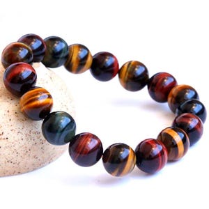 May include: A multi-coloured tiger's eye beaded bracelet with red, yellow and black stripes. The beads are round and have a smooth, polished finish.