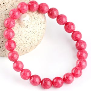 May include: A pink gemstone bracelet with round beads. The bracelet is made of natural stones and is a beautiful accessory for any occasion.