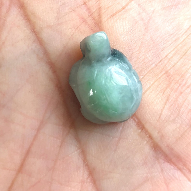 May include: A green jade turtle pendant. The turtle is carved in a realistic style and has a smooth, polished finish.