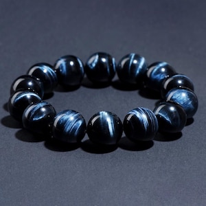 May include: A bracelet made of dark blue tiger's eye beads. The beads are round and have a smooth, polished finish. The bracelet is strung on a clear elastic cord.