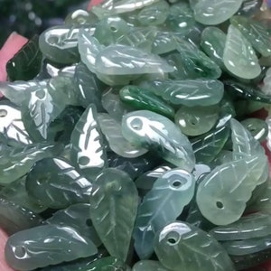 May include: A collection of green jade leaf-shaped pendants with a hole at the top for stringing. The pendants are carved with intricate details and have a smooth, polished finish.