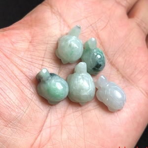 May include: Five small jade turtle figurines, carved in a light green color. The turtles are all facing the same direction, with their heads raised and their legs outstretched.