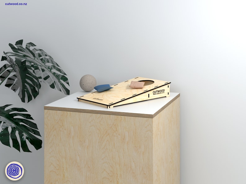 K&ouml;nnte beinhalten: Ein Holz-Beanbag-Wurfspiel mit einem braunen Beanbag auf der Plattform und einem blauen Beanbag auf dem Boden. Das Spiel wird von Cutwood hergestellt, einem Unternehmen, das ma&szlig;gefertigte Holzprodukte herstellt.
