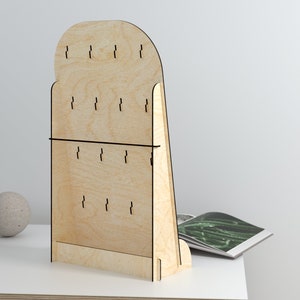 May include: A wooden earring display stand with a rounded top and a slanted base. The stand has multiple holes for hanging earrings.