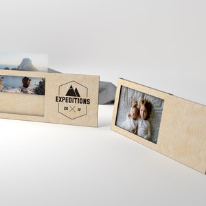 May include: Two wooden photo frames with a cutout for a photo. The frame on the left has a logo that says "EXPEDITIONS 20 x 12".