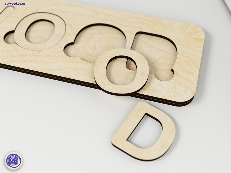 Puede incluir: Rompecabezas de madera con la palabra "GOOD" recortada. Las letras son piezas separadas que encajan en los recortes. Las piezas son de madera marr&oacute;n claro.