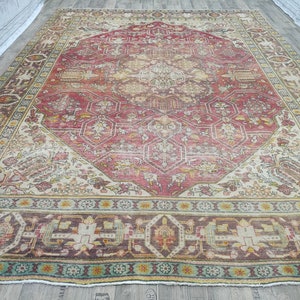 May include: A vintage Persian rug with a red, cream, and brown color scheme. The rug has a central medallion with intricate geometric patterns and a floral border.