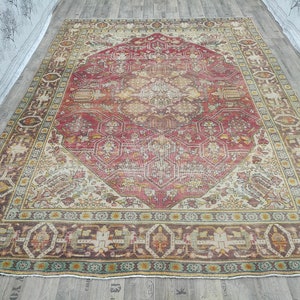 May include: A vintage rug with a red, cream, and brown color scheme. The rug has a central medallion with intricate floral patterns and a border with geometric designs.