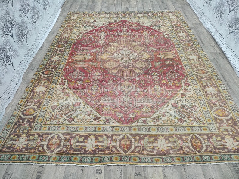 May include: A vintage rug with a red, cream, and brown color scheme. The rug has a central medallion with intricate floral patterns and a border with geometric designs.
