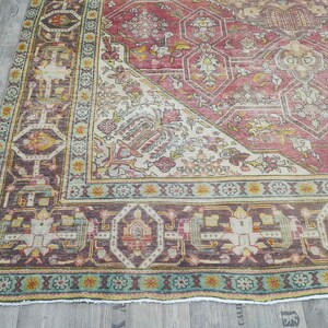 May include: A vintage rug with a red, white, and blue color scheme. The rug has a geometric pattern with intricate details. The rug is in good condition and has a worn look.