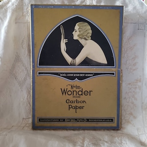 May include: Vintage Kee Lox Wonder Brand carbon paper box. The box is gold with blue trim and features an illustration of a woman applying makeup. Text on the box reads "YOU'LL LOOK YOUR BEST ALWAYS" and "Carbon Paper".