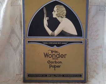 May include: Vintage Kee Lox Wonder Brand carbon paper box. The box is gold with blue trim and features an illustration of a woman applying makeup. Text on the box reads "YOU'LL LOOK YOUR BEST ALWAYS" and "Carbon Paper".