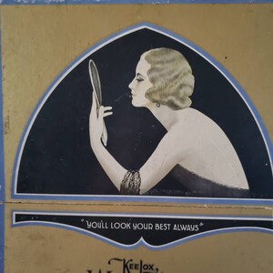 May include: Vintage illustration of a woman applying makeup, holding a mirror. The artwork features a woman with short, wavy hair, wearing a black dress and a bracelet. The text "YOU'LL LOOK YOUR BEST ALWAYS" is displayed below the image.