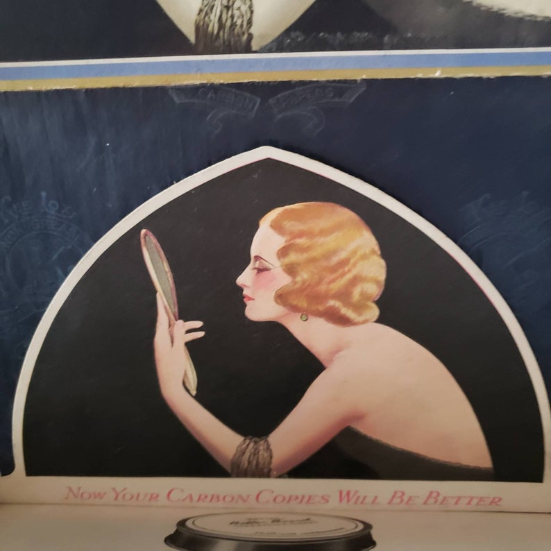 May include: Vintage advertisement featuring a woman looking in a hand mirror. The woman has blonde hair and is wearing a bracelet and earrings. The text "Now Your Carbon Copies Will Be Better" is visible at the bottom of the image.