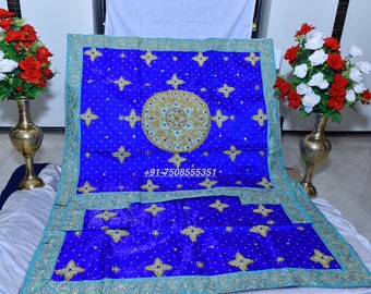 May include: A blue and gold embroidered fabric with a decorative design. The fabric has a light blue border and is decorated with gold stars and a large circular design in the center. The fabric is folded in half and the text +91-7508555351 is visible.