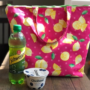 Peut inclure: Un sac isotherme rose &agrave; imprim&eacute; citron. Le sac est rempli d'une bouteille de Schweppes Ginger Ale et d'un pot de yaourt grec Chobani, saveur Myrtille.