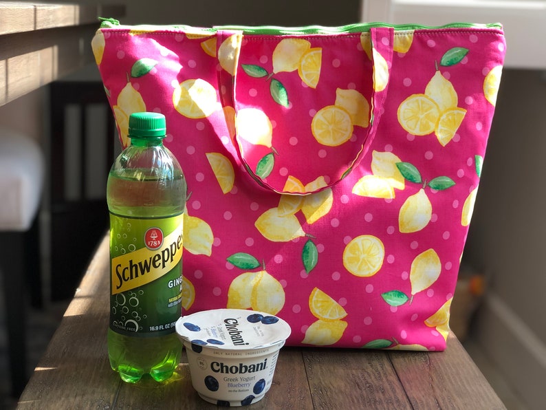 Peut inclure: Un sac isotherme rose &agrave; imprim&eacute; citron. Le sac est rempli d'une bouteille de Schweppes Ginger Ale et d'un pot de yaourt grec Chobani, saveur Myrtille.