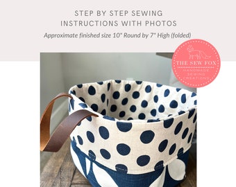 May include: A folded top hanging storage bag with a blue and white polka dot fabric and a blue fabric with white leaf designs. The bag has a brown leather handle and measures approximately 10 inches in diameter and 7 inches in height.