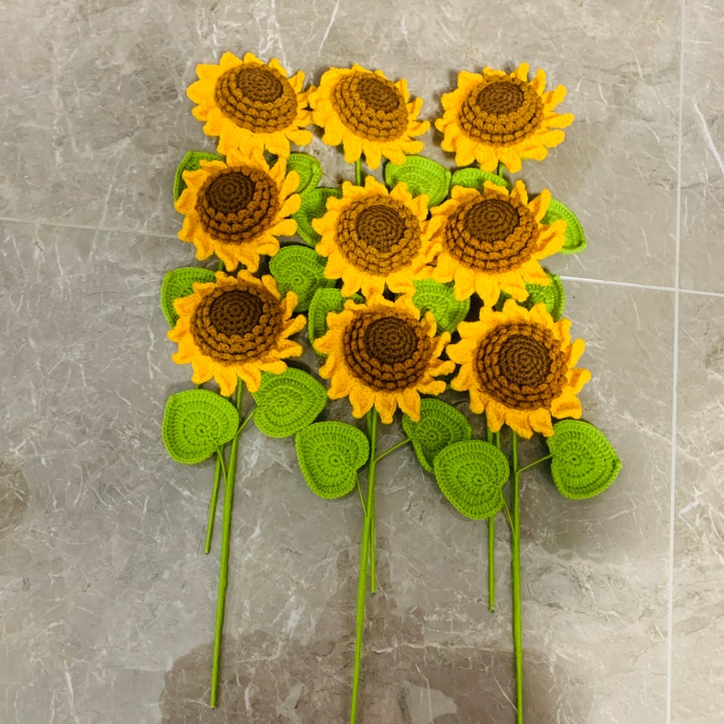 May include: A bouquet of crocheted sunflowers with green leaves. The sunflowers are yellow with brown centers.