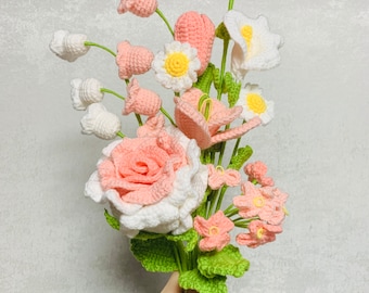 May include: A crocheted bouquet of flowers in shades of pink and white. The bouquet includes roses, lilies, and other delicate flowers.