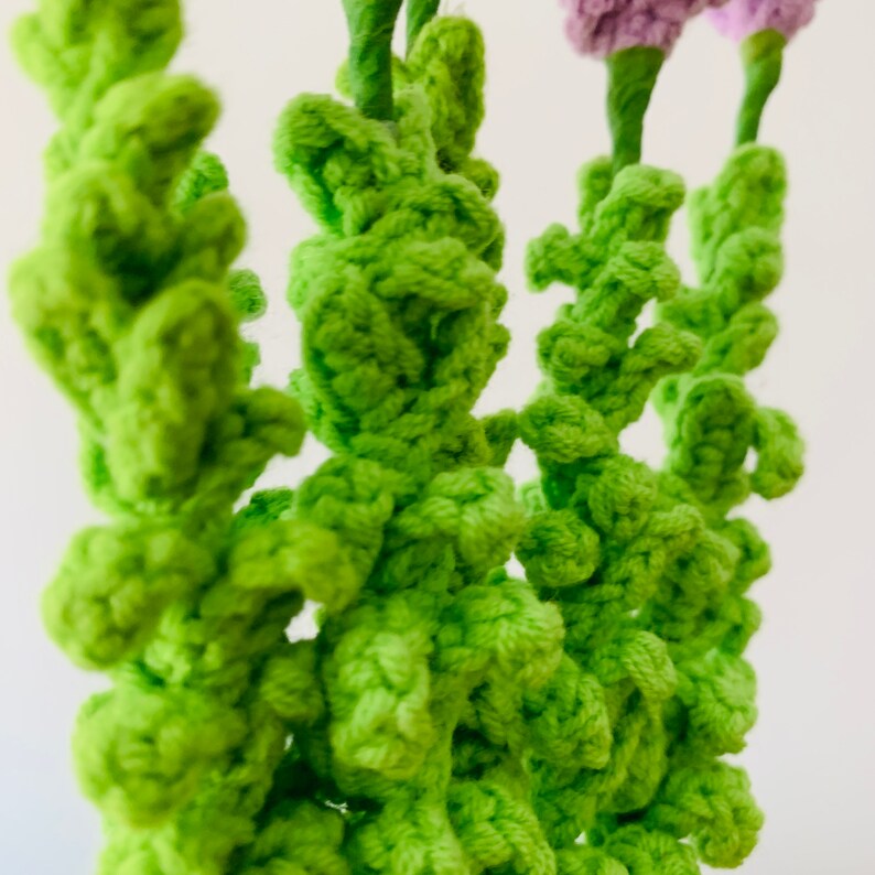 May include: Close-up of a crocheted bouquet of green flowers. The flowers are made with a textured, bumpy yarn.