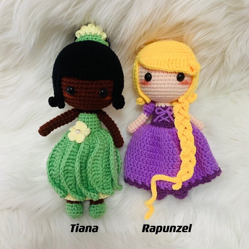 Peut inclure: Deux poup&eacute;es en crochet, l'une avec des cheveux noirs et une robe verte, l'autre avec des cheveux blonds et une robe violette. Les poup&eacute;es sont &eacute;tiquet&eacute;es "Tiana" et "Rapunzel".
