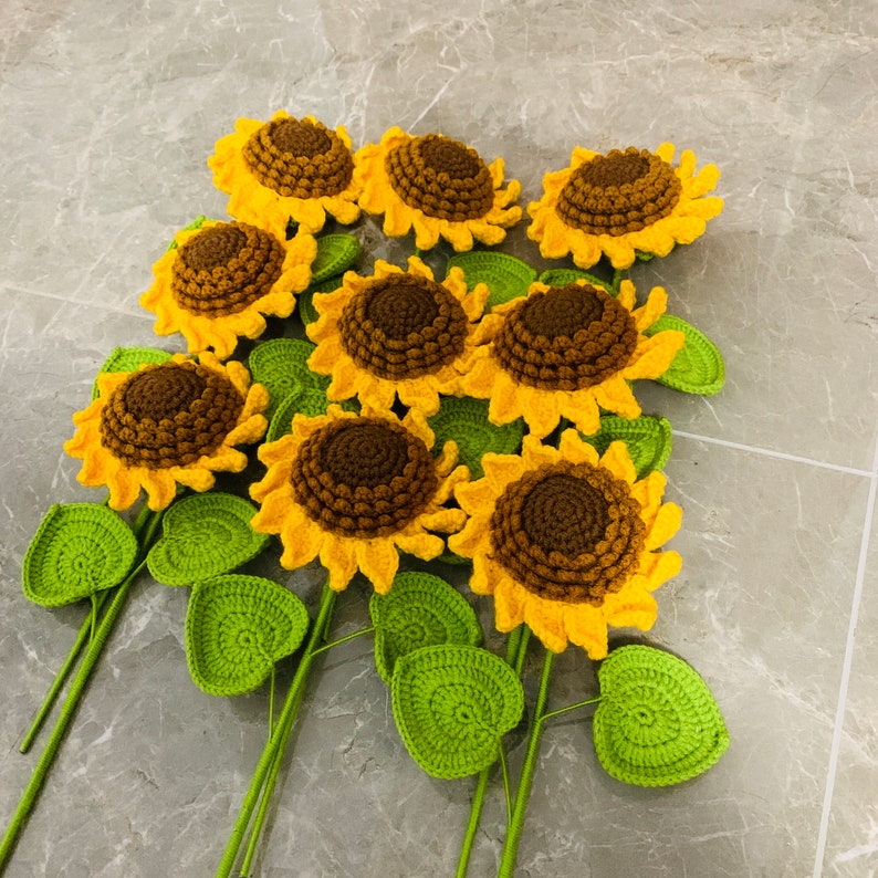 May include: A bouquet of crocheted sunflowers with green leaves. The sunflowers are yellow with brown centers and the leaves are a bright green.
