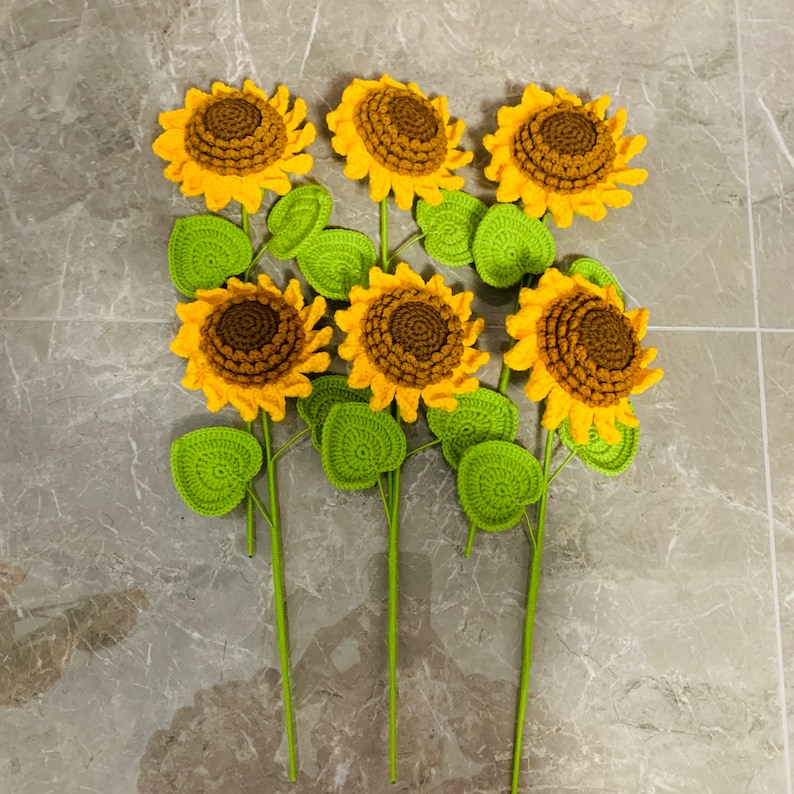 May include: A bouquet of six crocheted sunflowers with green leaves. The sunflowers are yellow with brown centers.