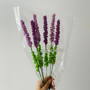 May include: A bouquet of purple and green crocheted lavender flowers in a clear plastic bag with the word "Love" written on it.