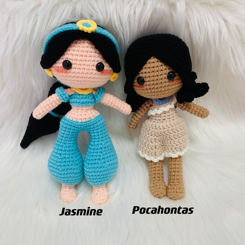 Peut inclure: Deux poup&eacute;es en crochet, l'une avec un pantalon bleu et un bandeau jaune, l'autre avec une robe marron. La poup&eacute;e avec le pantalon bleu est &eacute;tiquet&eacute;e "Jasmine" et la poup&eacute;e avec la robe marron est &eacute;tiquet&eacute;e "Pocahontas".