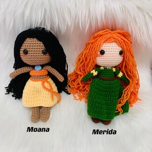 Peut inclure: Deux poup&eacute;es en crochet, l'une avec des cheveux noirs et une robe orange et jaune, l'autre avec des cheveux orange et une robe verte. Les poup&eacute;es sont &eacute;tiquet&eacute;es "Moana" et "Merida".