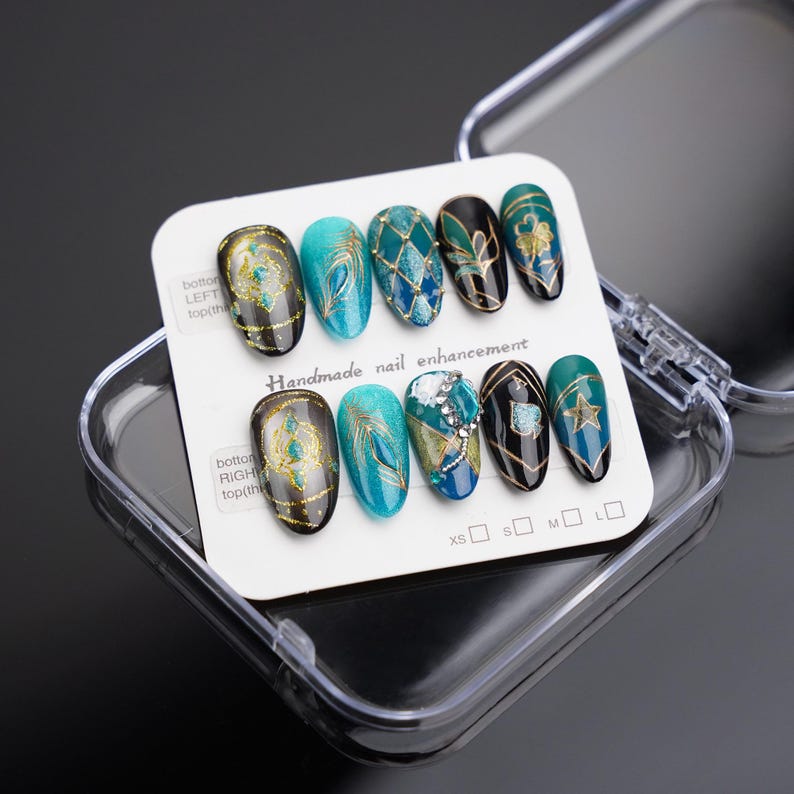 May include: A set of ten false nails with different designs featuring turquoise, gold, and black colors. The nails are displayed in a clear plastic case with a white card that reads "Handmade nail enhancement".
