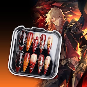 May include: A set of ten false nails in a clear plastic case. The nails are long and pointed, with a red, black and gold design. The design features flames, jewels and a dragon.