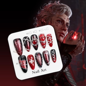 May include: A selection of nail art designs on a white card. The nails showcase various designs in red, black, and silver, including intricate patterns, gems, and metallic details. The card is labelled "Nail Art".