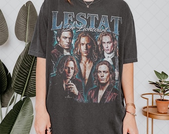 Puede incluir: Camiseta gris oscuro con un gráfico de varias personas y el texto "LESTAT De Lioncourt" en azul. La camiseta tiene un aspecto vintage y desgastado, con las palabras "PEPPER COLORS" en la parte inferior.