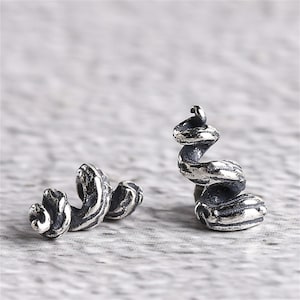 Könnte beinhalten: Ein Paar silberne Ohrringe mit einem Spiraldesign. Die Ohrringe sind aus strukturiertem Metall gefertigt und haben eine einzigartige, organische Form.