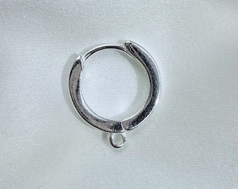 May include: A silver-toned circular hoop earring component featuring a hinged closure mechanism and a small, integrated jump ring at the bottom for attaching charms or other decorative elements to the jewelry piece.