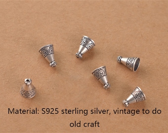 Könnte beinhalten: Sechs kleine, silberfarbene, kegelförmige Perlen mit kunstvollen floralen Designs. Die Perlen sind auf einer braunen Oberfläche verstreut. Der Text unten im Bild lautet: Material: S925 Sterlingsilber, Vintage für altes Handwerk.