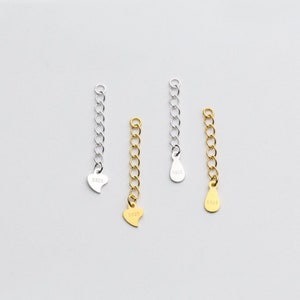May include: Three silver and gold chain extenders with heart and teardrop charms. The charms are stamped with the number "S925".